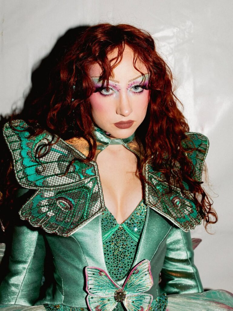 Chappell Roan com roupa verde e cabelo cacheado ruivo com franja