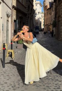 Mulher de pele clara, com vestido amarelo-manteiga e bolsa azul