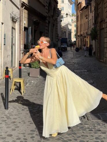 Mulher de pele clara, com vestido amarelo-manteiga e bolsa azul