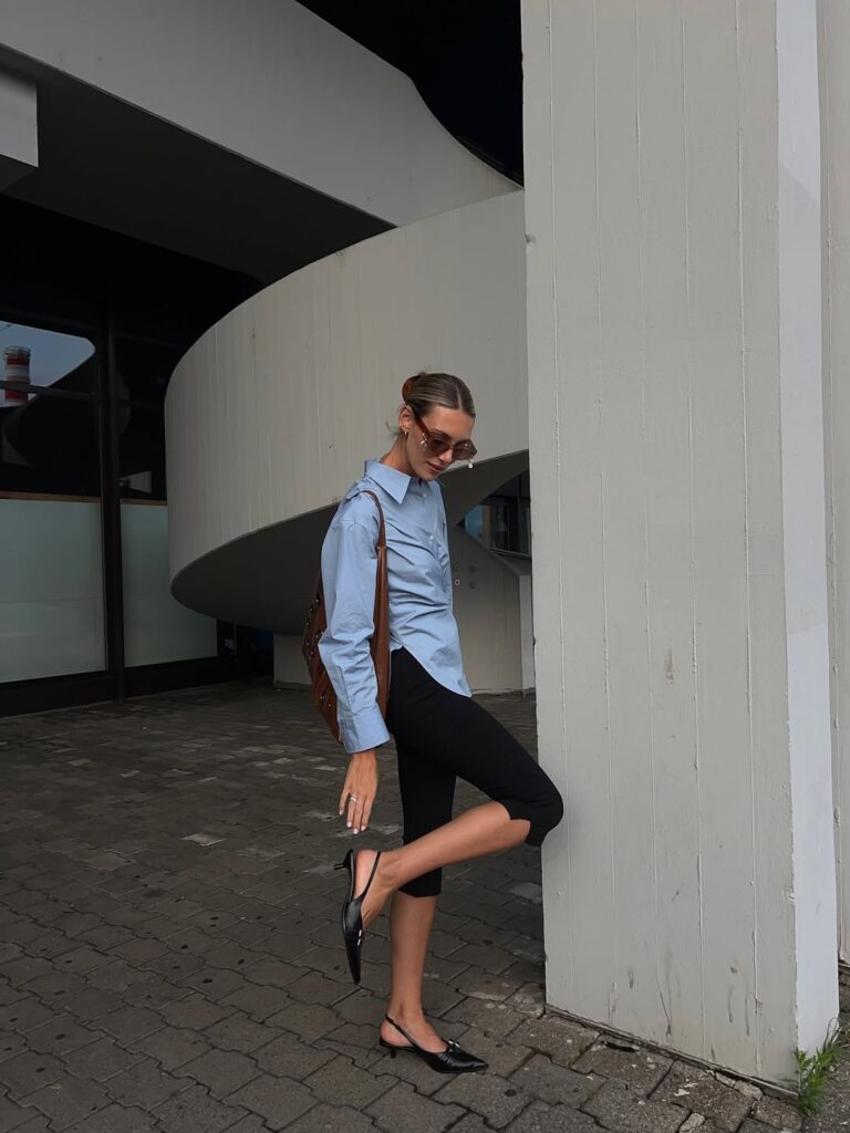 Mulher jovem com camisa azul claro, calça capri e slingback