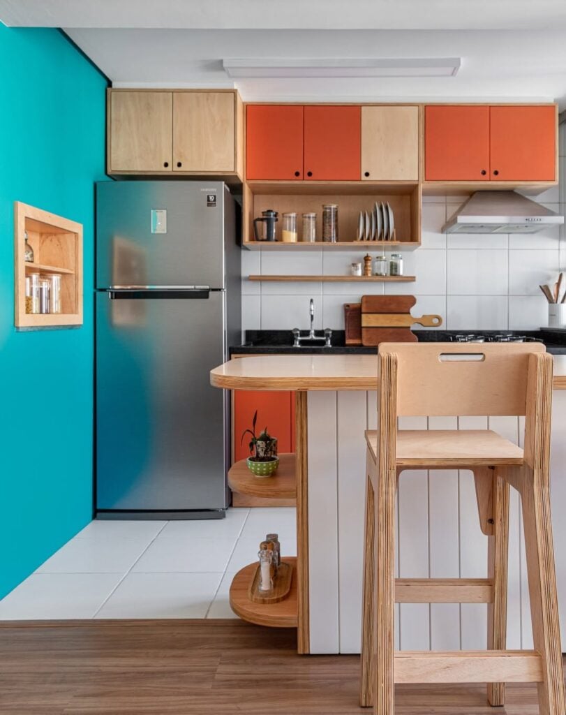 Cozinha com parede azul e armários amadeirados e laranja