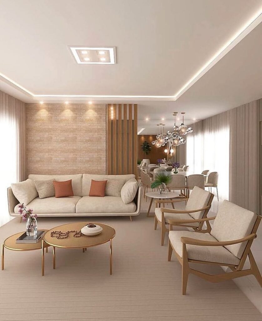 Sala de estar com sofá bege e almofadas terrosas, poltronas de madeira com assento estofado