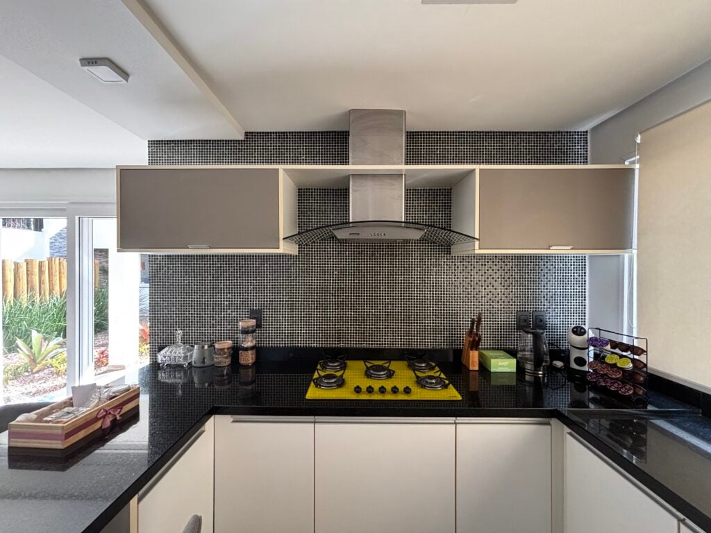 Cozinha com bancada preta e armários aéreos cinza
