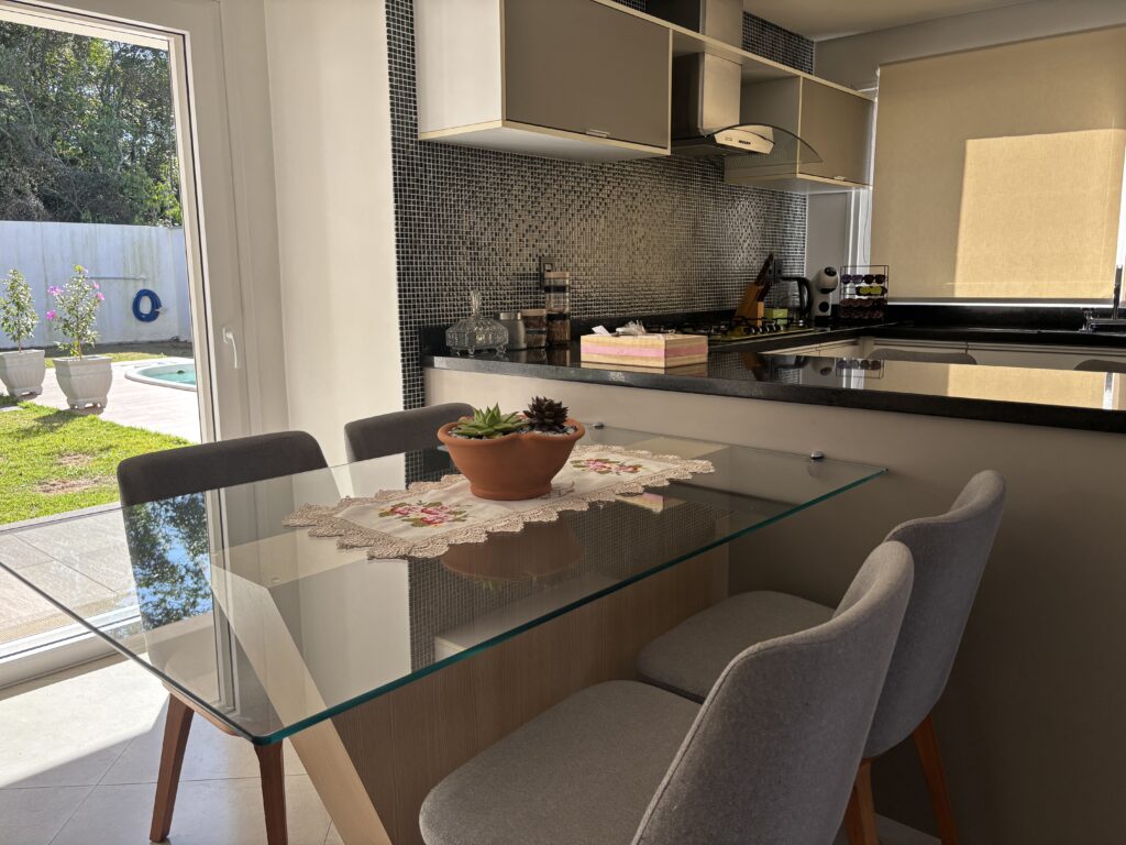 Mesa com tampo de vidro e cadeiras estofadas cinza