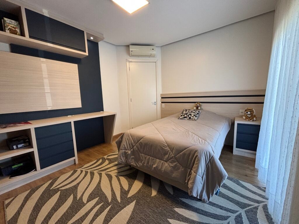 Quarto com grande tapete cinza e bege, armários, gavetas e parede em azul