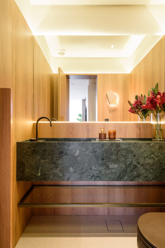 Lavabo com painéis amadeirados e pedra verde na bancada