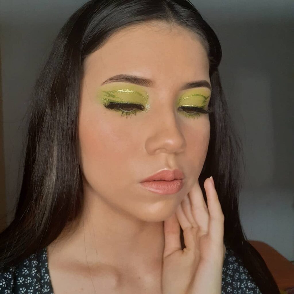 Mulher de pele clara, com cabelo preto e maquiagem em tons de verde neon 