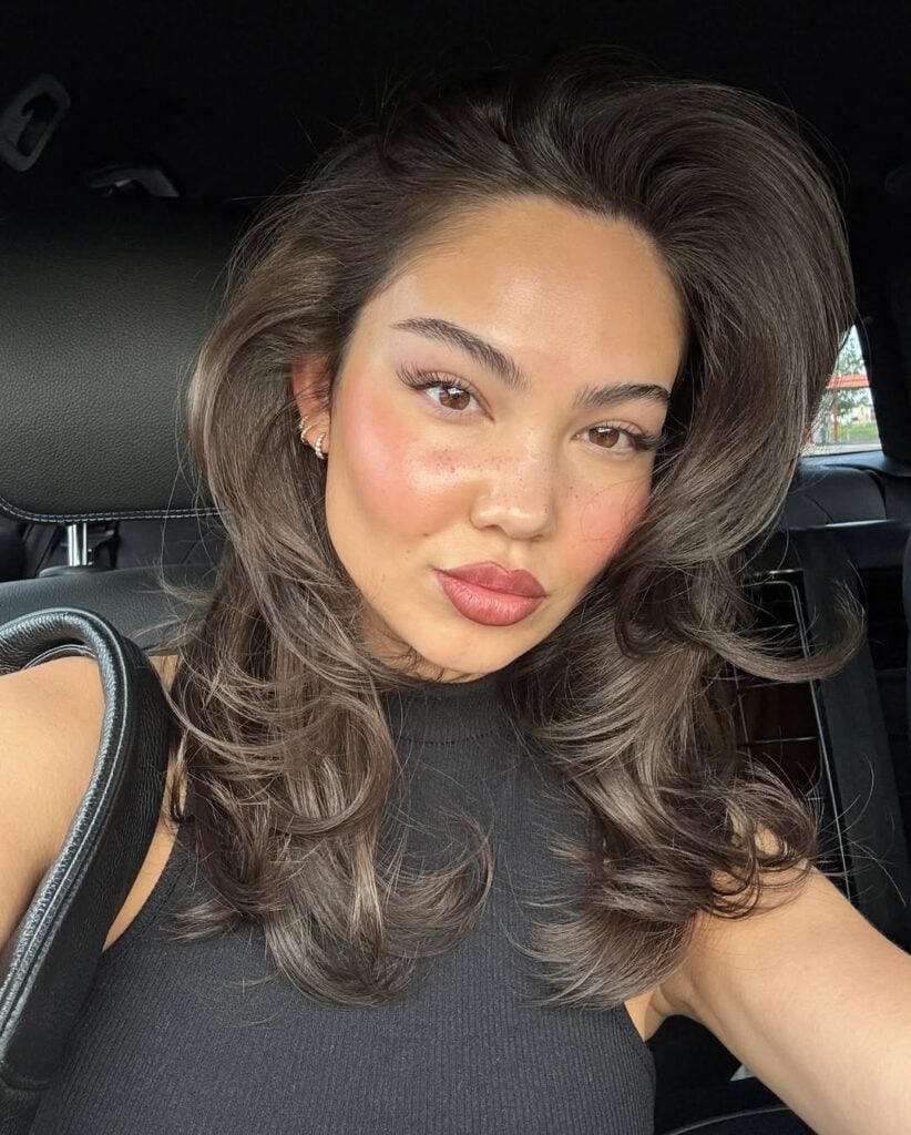 Mulher de pele clara, com blusa preta, cabelo escuro e maquiagem do dia a dia