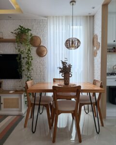Sala de jantar com mesa e cadeiras de madeira e pendente de fibras naturais