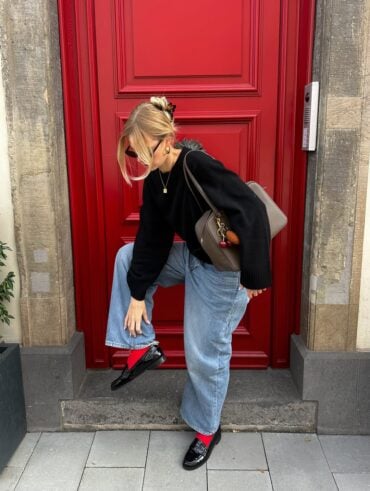 Mulher jovem com look de inverno composto por jeans, suéter e mocassim