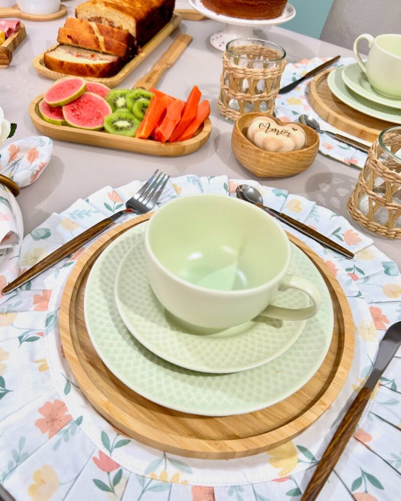 Mesa posta com jogo americano floral e louças verde-claro