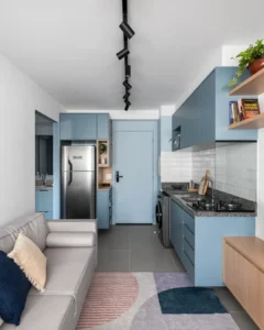 Sala com sofá cinza integrada com cozinha azul e paredes brancas
