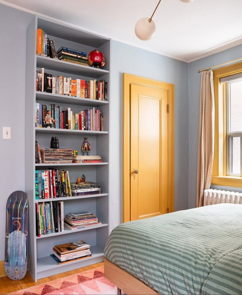 Quarto com paredes e estante azul-claro, porta e janela amarelas