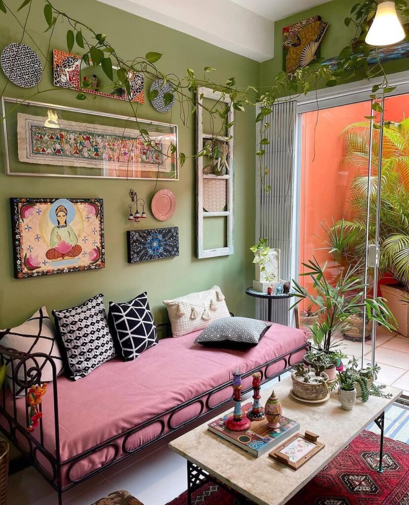 Sala de estar com parede verde, sofá com estrutura em metal com almofadas e quadros na parede