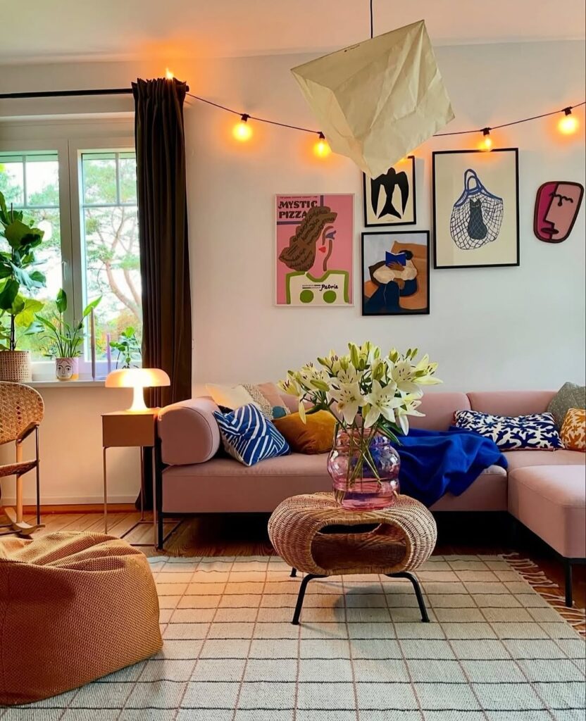Sala de estar com sofá em tom de rosa antigo, quadros e mesa de centro em fibra natural