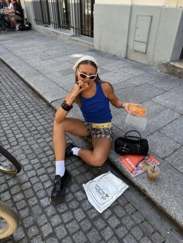 Mulher jovem usando regata azul, bermuda e mocassim com meia