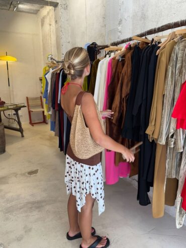 Mulher escolhendo roupas em arara
