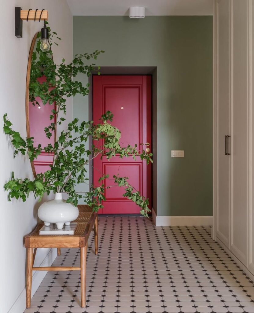 Corredor com parede verde e porta rosa