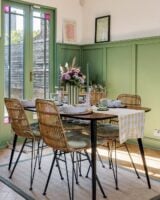 Ambiente com mesa, cadeiras, vaso com listras verde e brancas