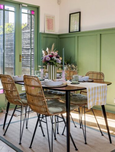 Ambiente com mesa, cadeiras, vaso com listras verde e brancas