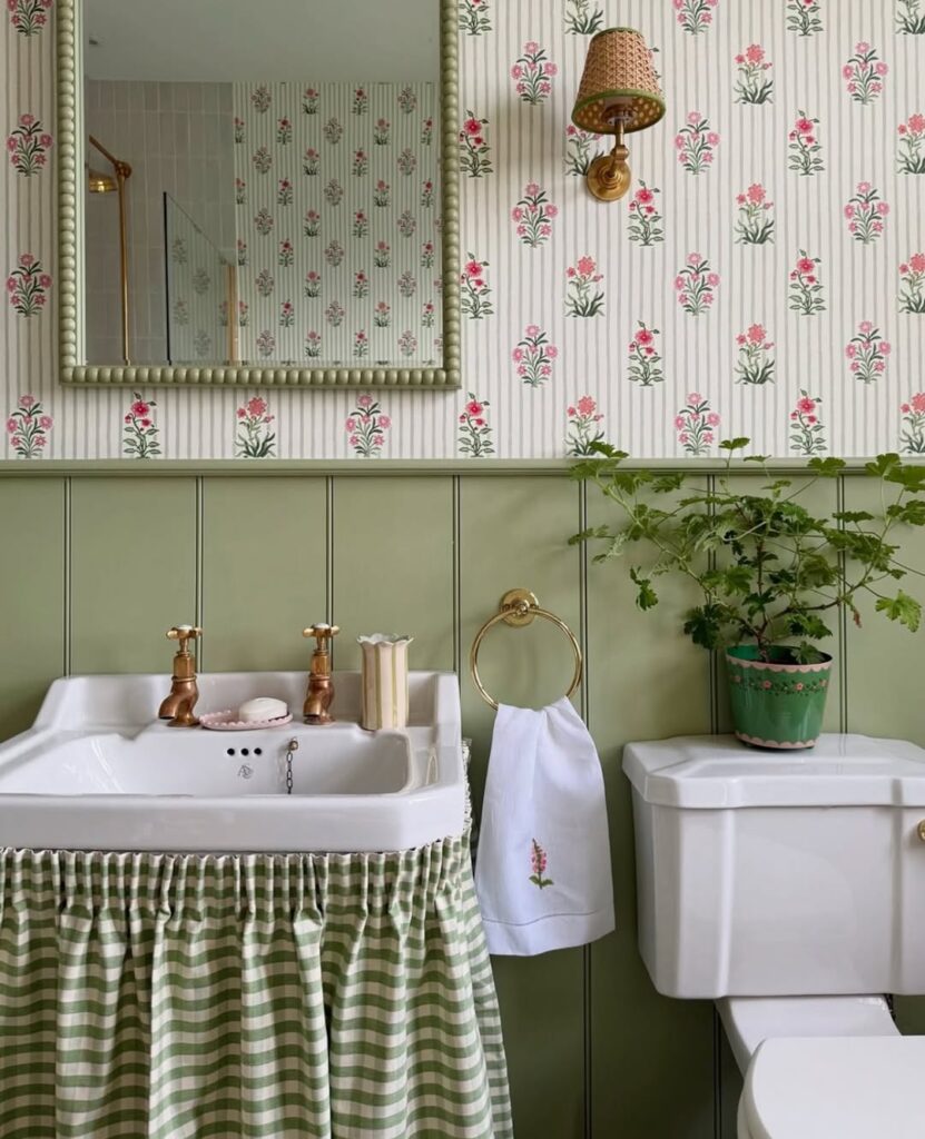 Banheiro com meia parede em verde e parte com papel de parede floral