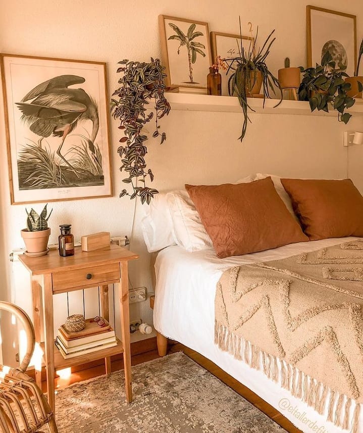 Quarto no estilo boho com almofadas terrodas, prateleira com planta suspensa e msa de cabeceira com gaveta