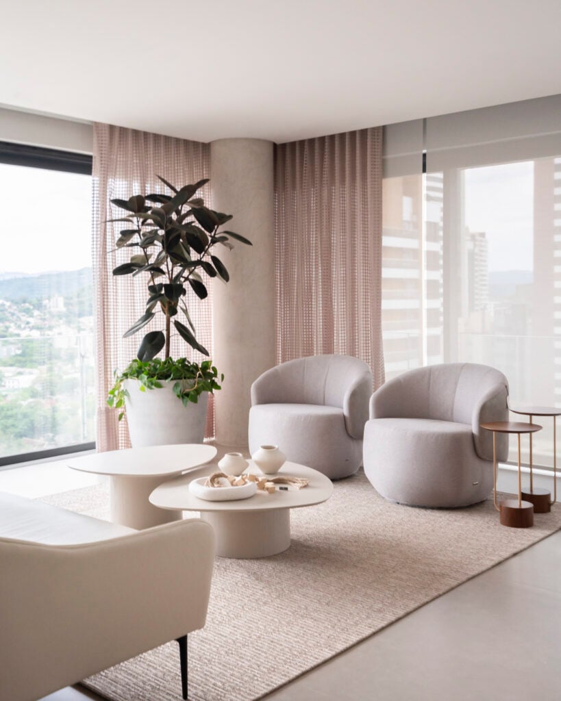 Sala de estar com grande tapete, poltronas estofadas e vaso com plantas
