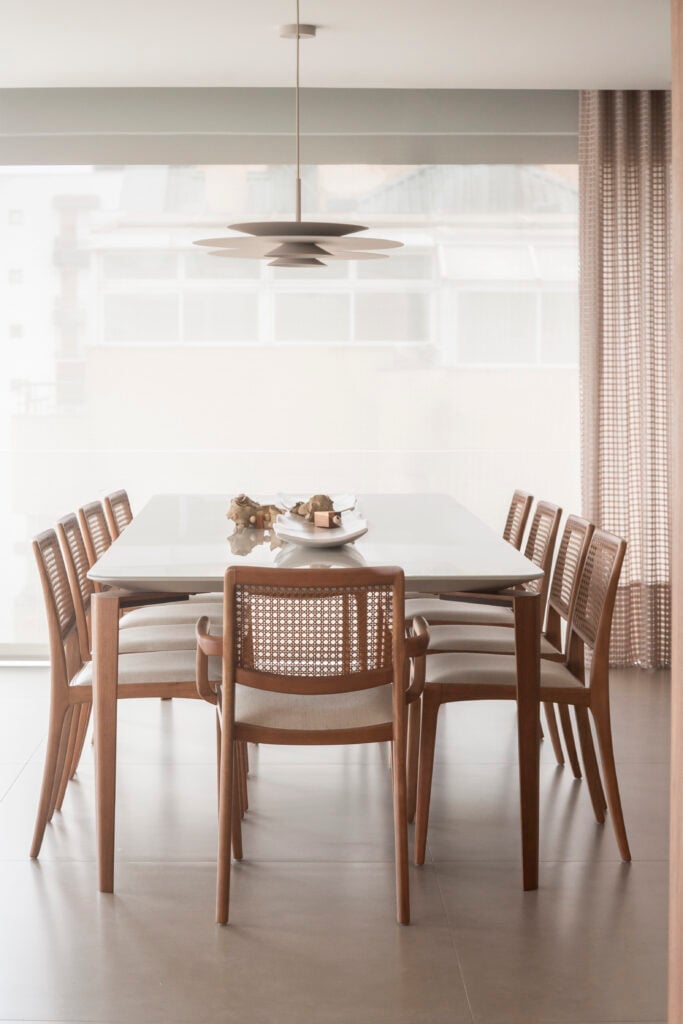 Sala de jantar com mesa retangular e cadeiras de madeira com encosto de telinha