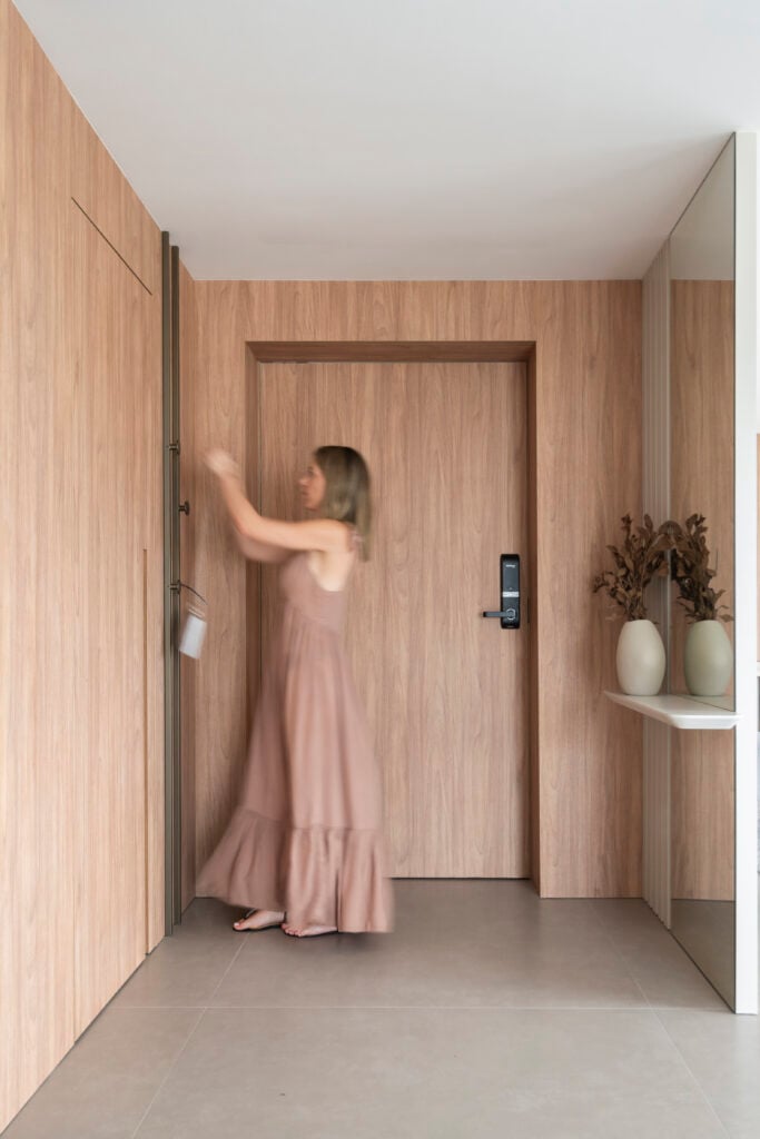Hall de entrada com painéis amadeirados e mulher de vestido nude