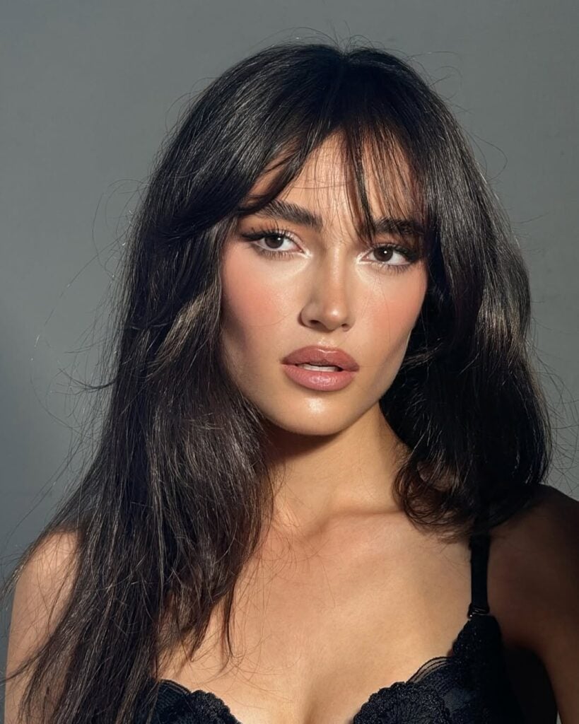 Mulher de pele clara, com cabelo escuro e sobrancelhas marcadas