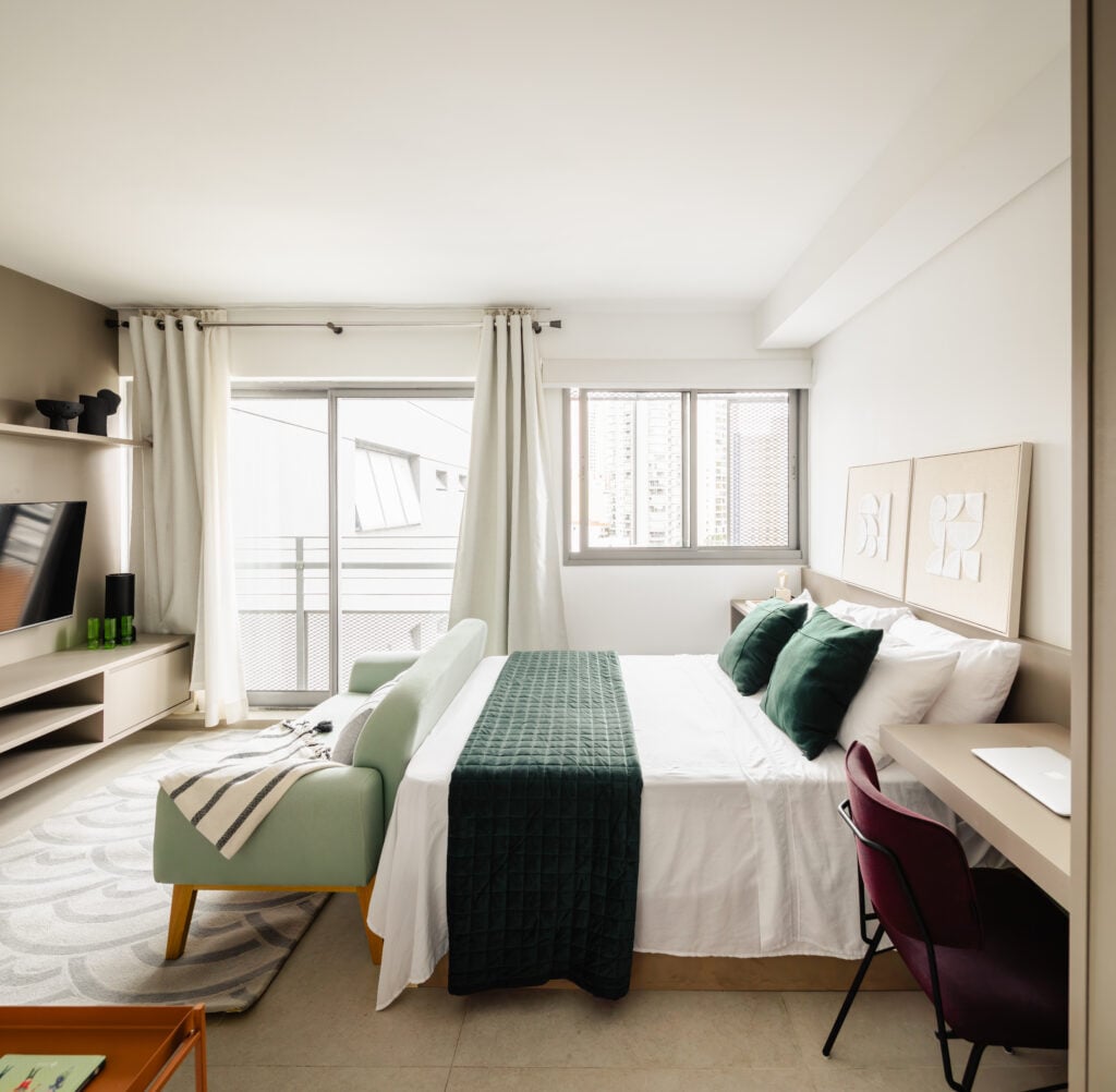 Quarto integrado ao living em tons claros e almofadas verde