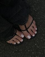 Pés de pele clara, com sapato aberto e unhas dos pés com francesinha