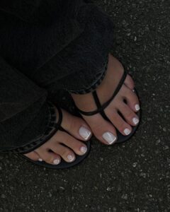 Pés de pele clara, com sapato aberto e unhas dos pés com francesinha