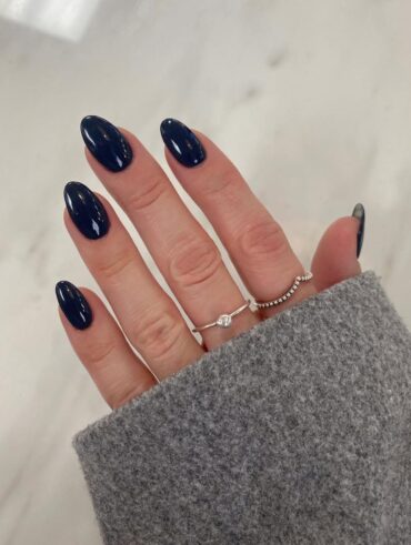 Mão de pele clara, com anéis em prata e unha amendoada azul-marinho