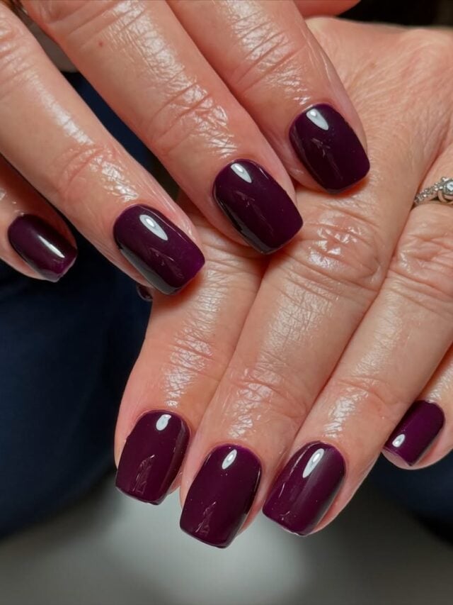 Mãos de pele clara, com anel de brilhantes e unha quadrada roxo-escuro
