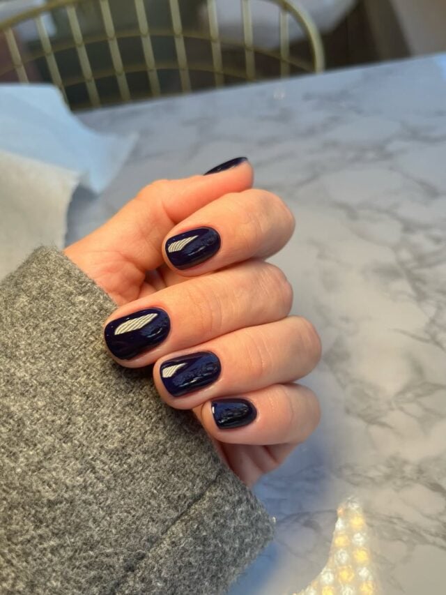 Mão de pele clara, com unha oval azul-marinho
