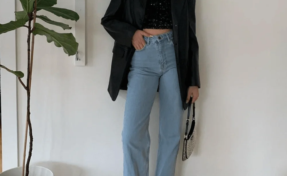Mulher jovem e magra com blazer, calça jeans e top de paetê