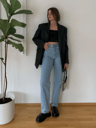 Mulher jovem e magra com blazer, calça jeans e top de paetê
