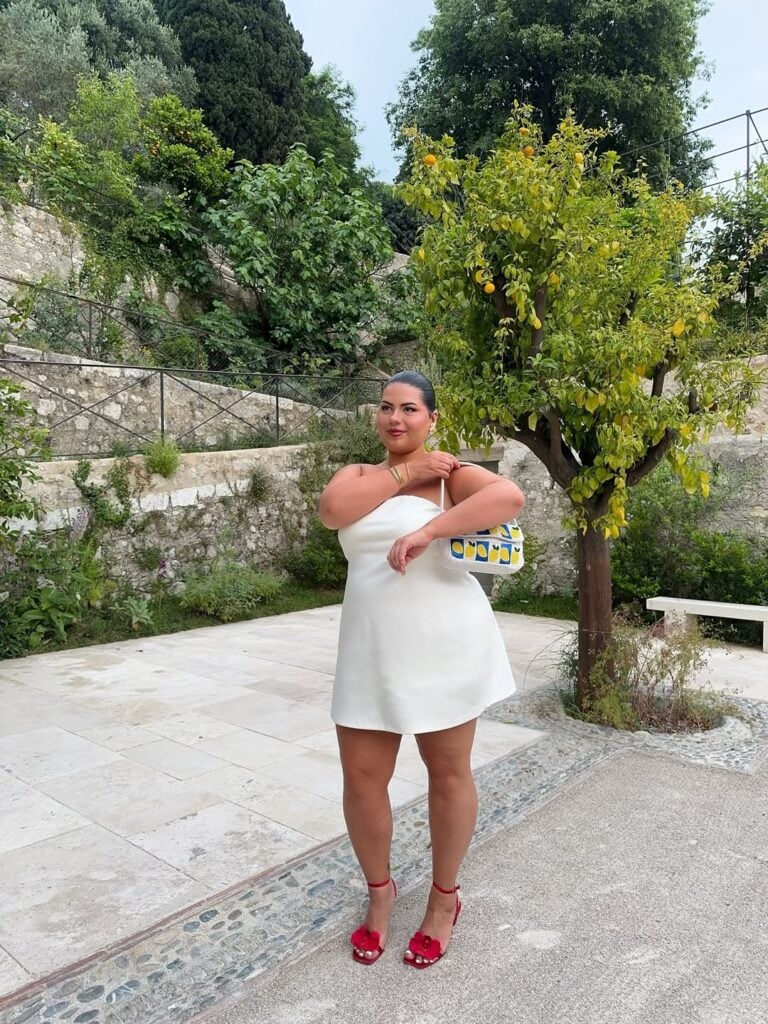 Mulher jovem com vestido branco e sandália de salto alto vermelha