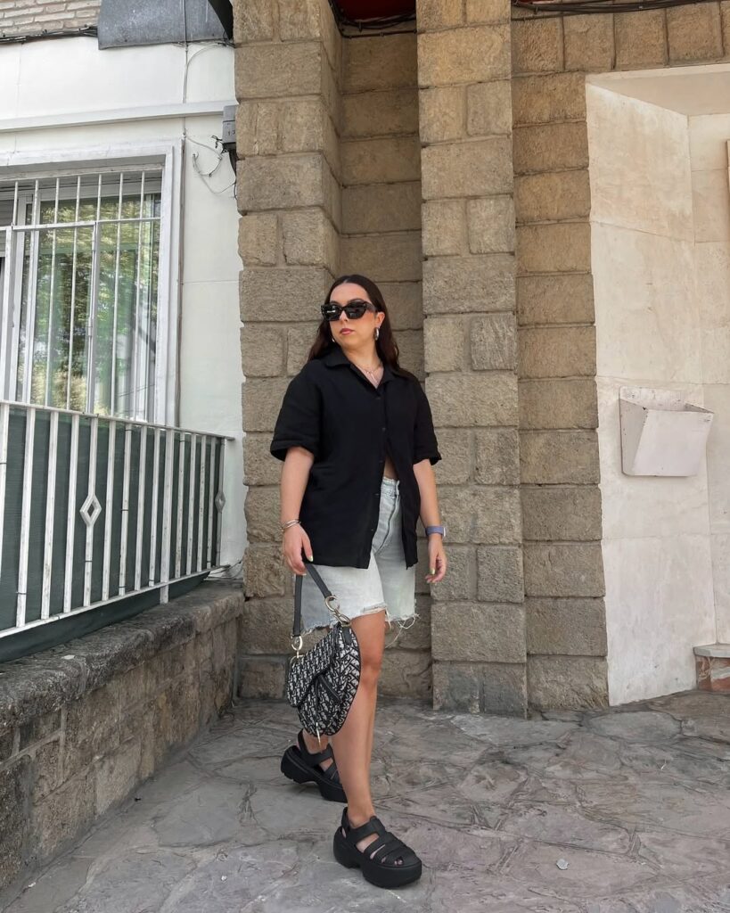 look para festival com camisa preta, bermuda jeans e sandália preta