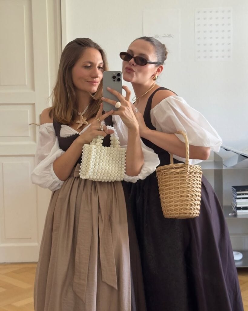 Duas mulheres em foto na frente do espelho. elas usam traje estilo Oktoberfest
