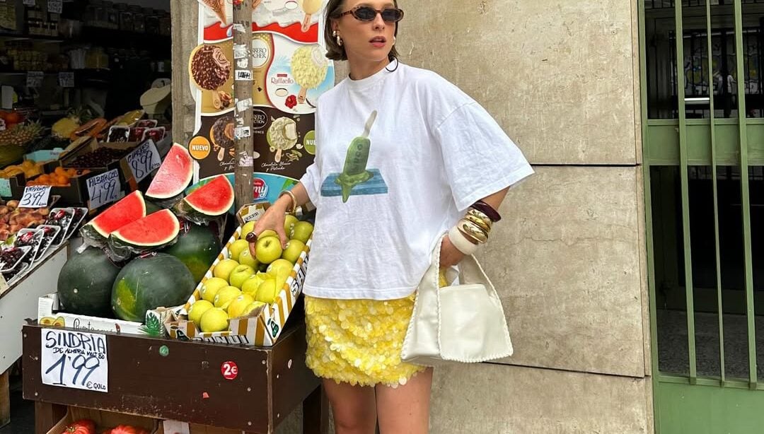 mulher jovem de pele clara usando saia de paetê amarela, camiseta estampada e salto amarelo