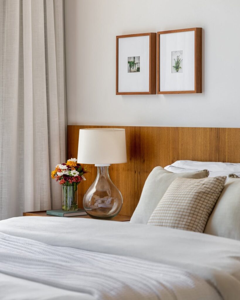 Quarto com paredes e cortina branca com cabeceira de madeira