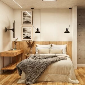 Quarto em tons neutros com quadros na parede e cabeceira amadeirada com escrivaninha