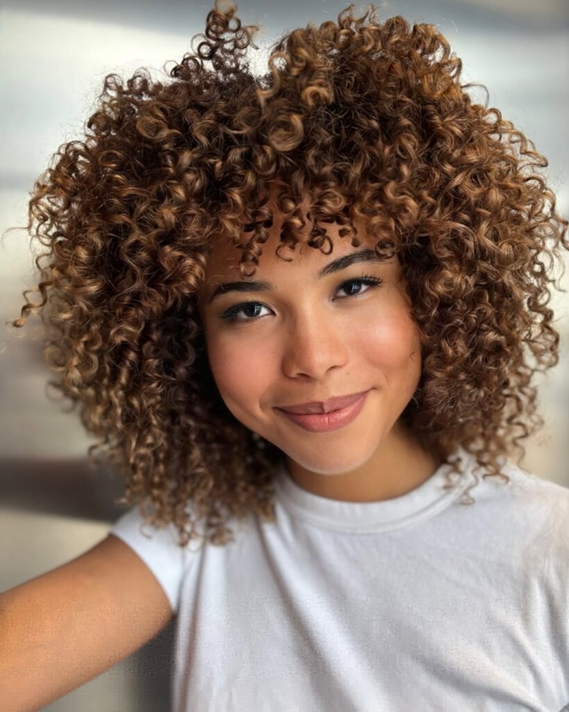 Mulher de pele clara com cabelo cacheado iluminado