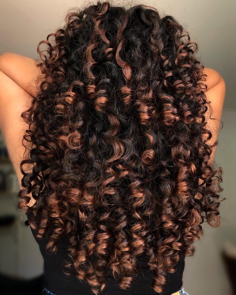 Mulher com cabelo cacheado com a técnica morena iluminada