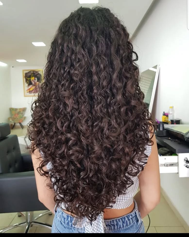Mulher de pele clara com cabelo longo cacheado cortado em v