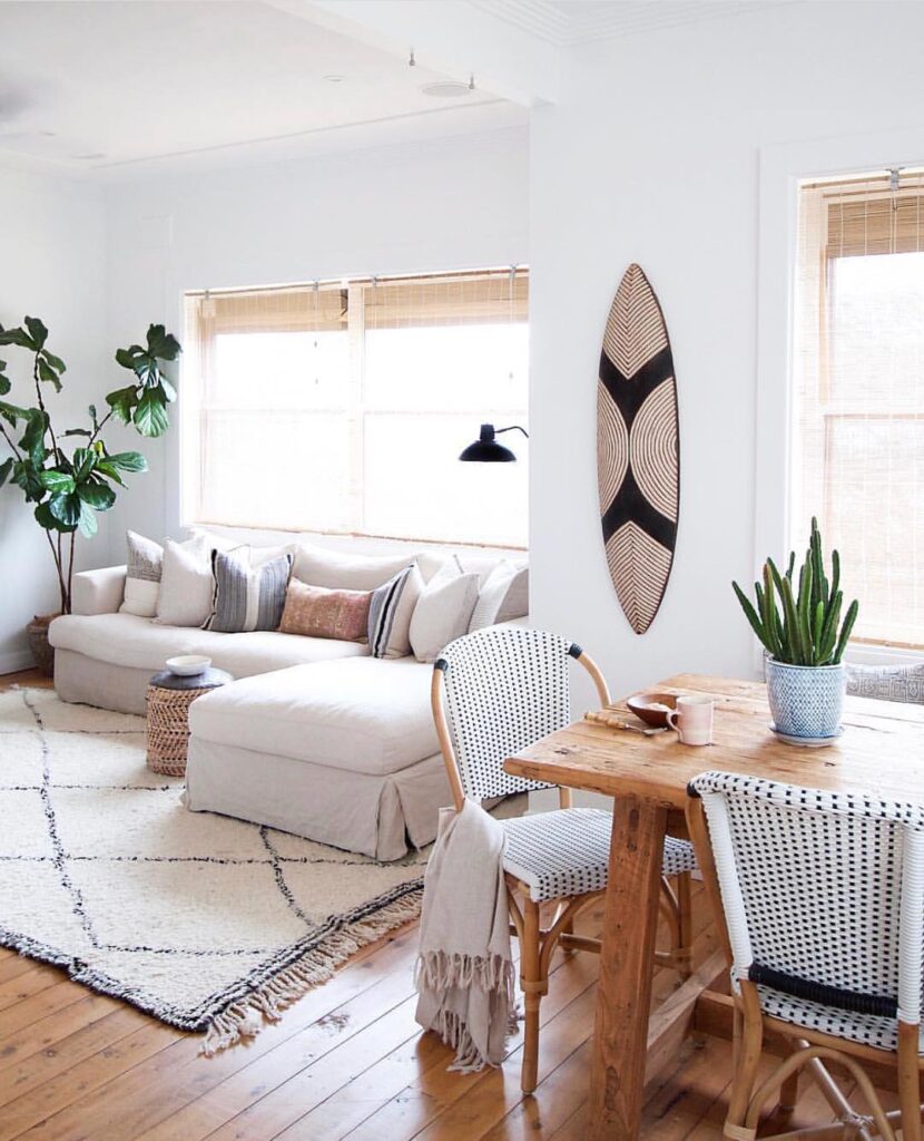 Decoração de casa de praia com sofá claro, mesa de madeira com vaso de planta
