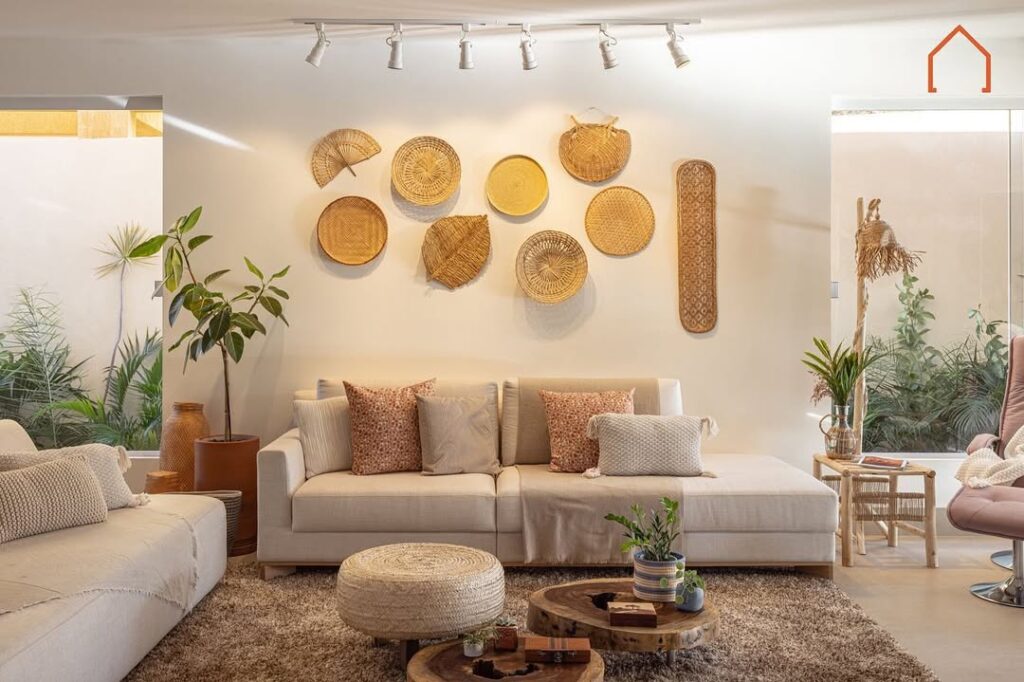 Sala de casa de praia com sofás claros, itens de fibras naturais na parede e spots de luz