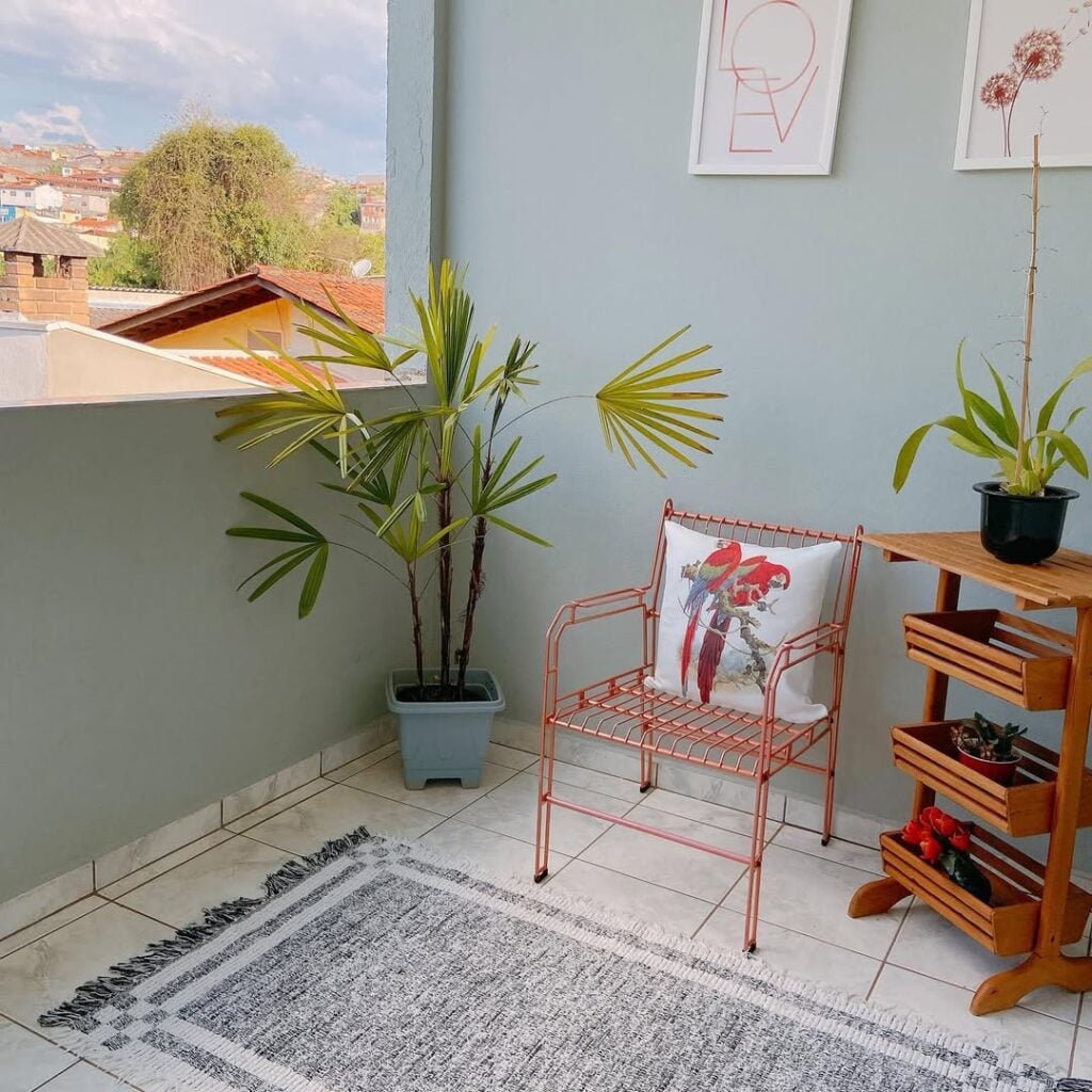 Varanda externa com plantas, quadros e cadeira aramada rosé